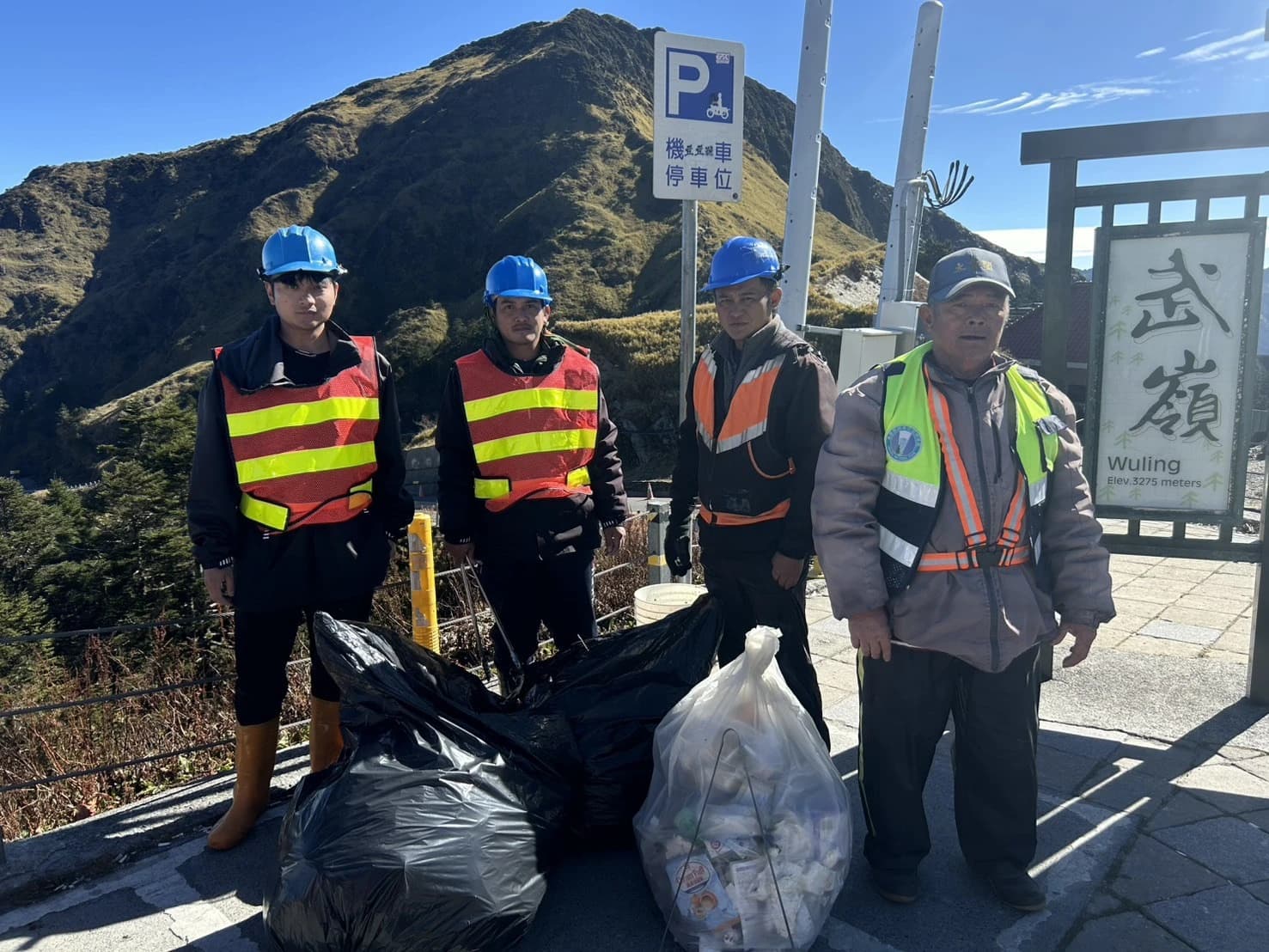 工作人員於合歡山公路護欄外的邊坡撿拾清理垃圾