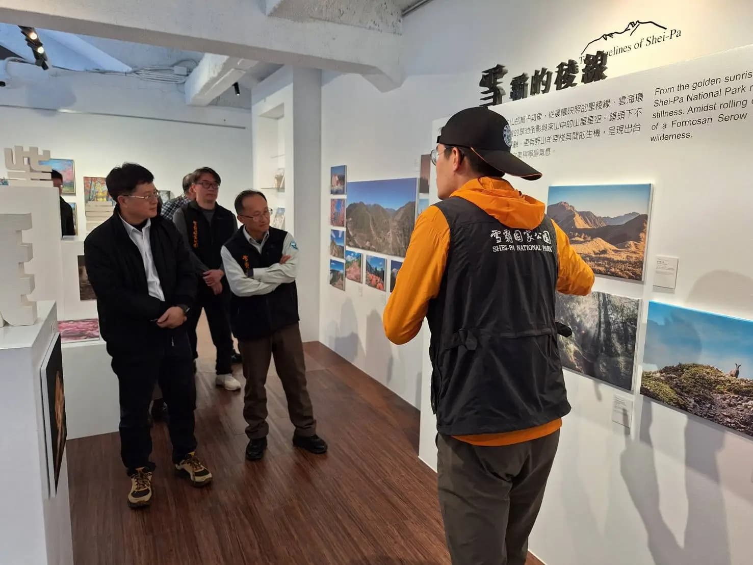 國家公園署王成機署長率領國家公園署團隊參觀藝啟武陵首展,武陵站巡查員徐偉哲向署長介紹他的攝影作品。