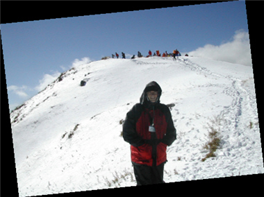 在湛藍的天空下，羅明瑞與山友踩著皚皚白雪，往山頭前進。/羅明瑞提供