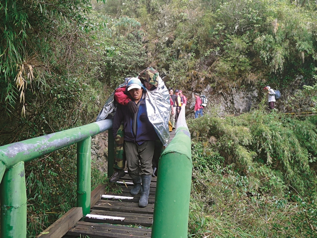 以頭帶輔助背負傷者下山。