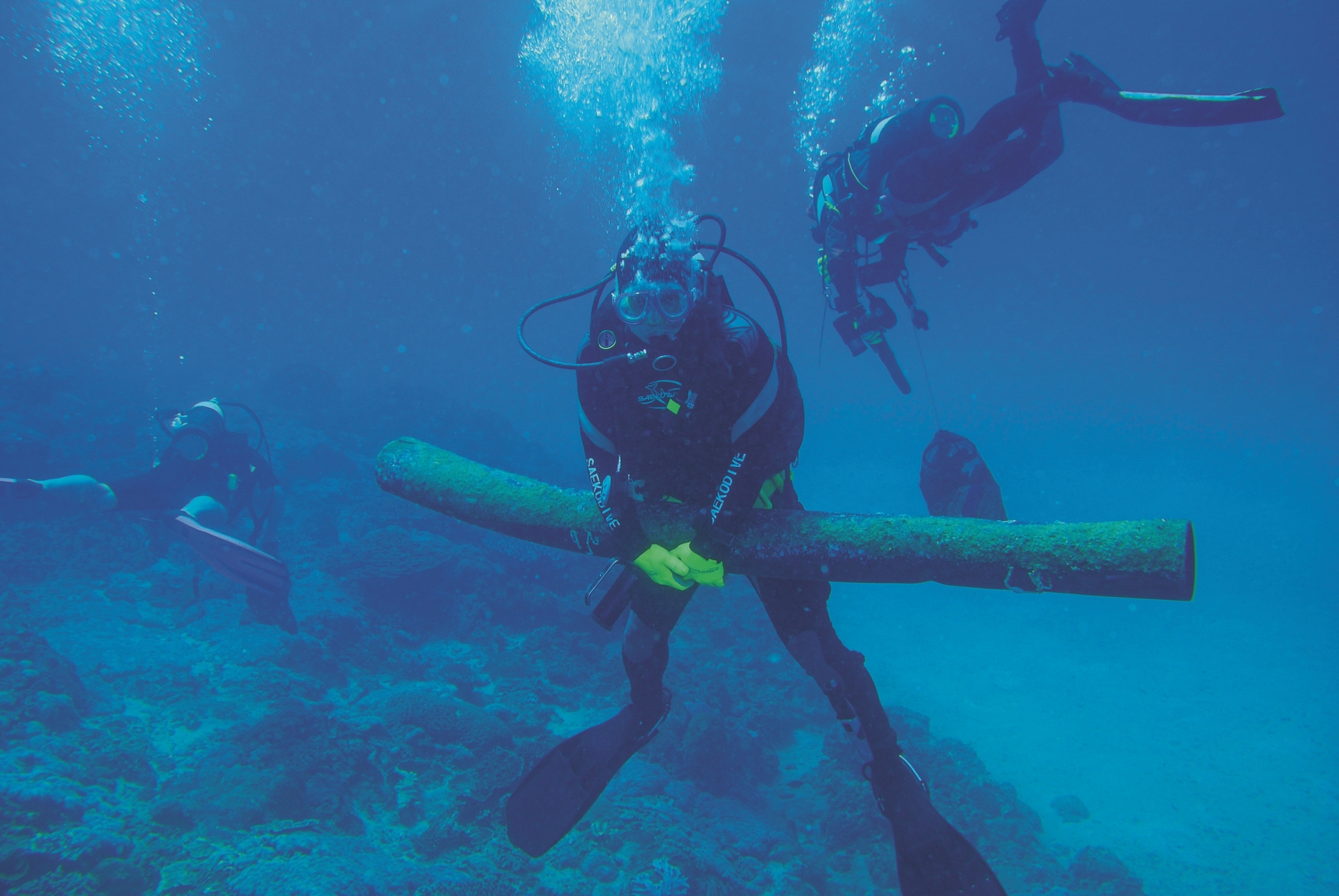 淨海志工抱起躺在海底許久的成捆黑色塑膠墊/黃興倬 提供