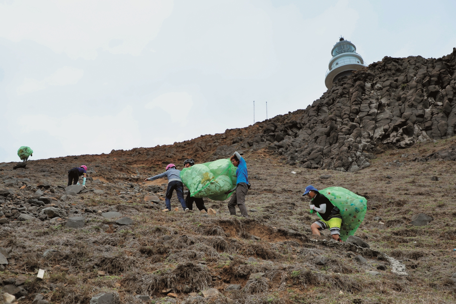 錦湖國小學童在東吉管理站張哲豪協助下，大小拉小手，在東吉燈塔下搬運海漂垃圾／吳明翰 攝