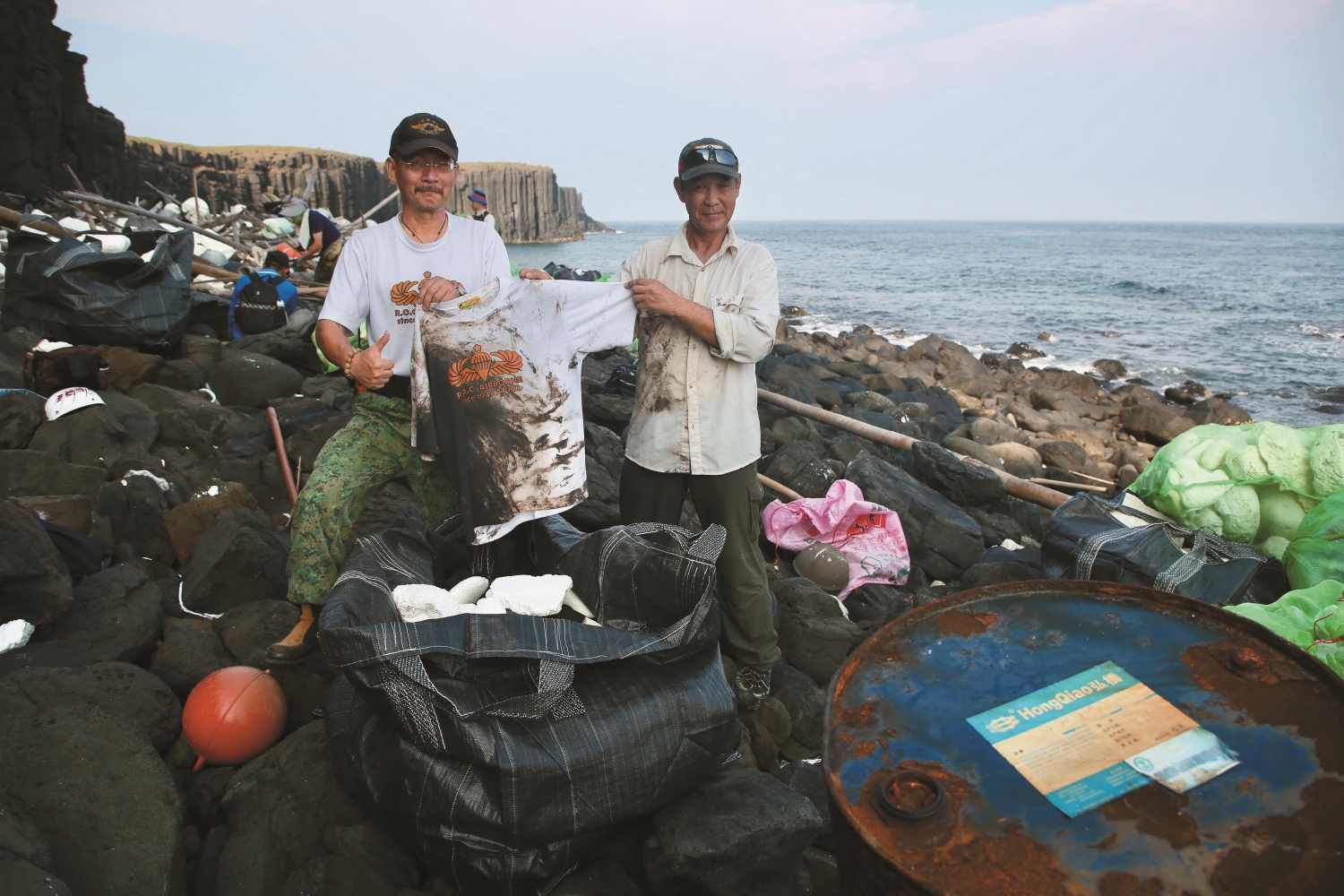 為了淨灘，特戰志工的衣服髒了又換，換了又髒（左：黃錫榮、右： 退役空特士官長陳桔雲）／吳明翰 攝