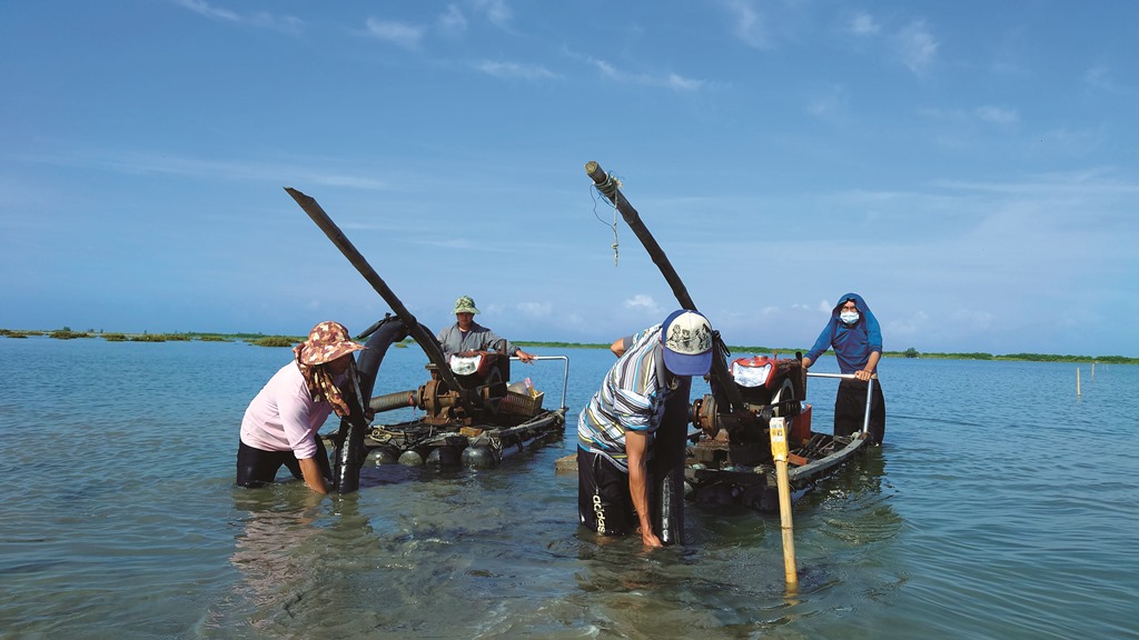 ｜利用採收文蛤的管筏幫浦水柱沖出人工潮溝／邱郁文 攝