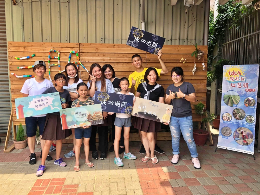 遊戲結束後，參加者舉著「成功過關」牌卡，開心大合照(臺南市三股社區發展協會提供)