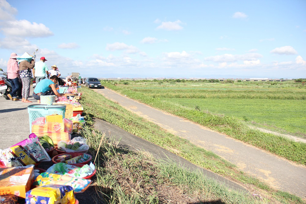 居民拜溪時多朝向溪流並於堤防擺上祭品，此例為2015年中港仔拜溪王場景(台江國家公園管理處提供)