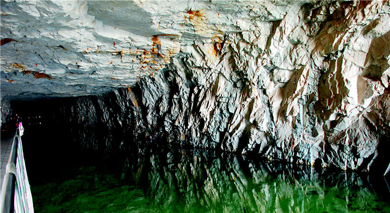 The water channel in winter is calm, clearly reflecting the rocks above it. 