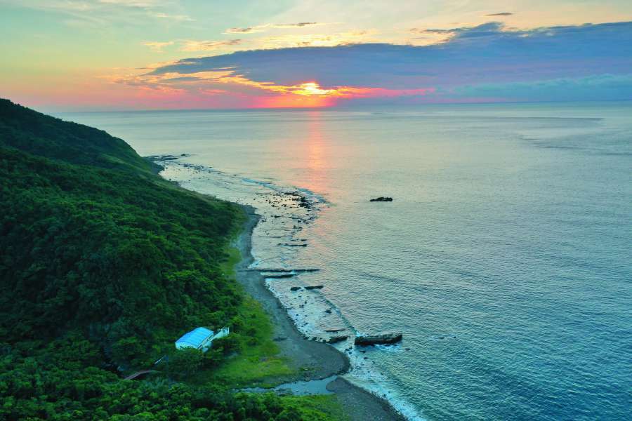 黃昏的溪仔口海岸，可見廢棄海巡崗哨的藍屋頂／陳忠能 攝